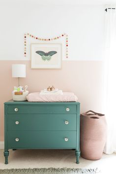 a baby's crib in a pink and green nursery with a painting on the wall