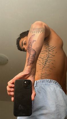 a man with a tattoo on his arm holding a cell phone