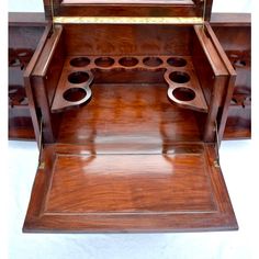 an antique wooden shelf with two cups on it's top and one drawer open