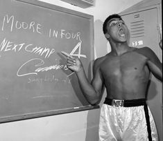 a man standing in front of a blackboard with writing on it and pointing to the side