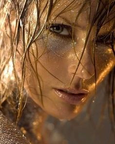 a close up of a woman's face with water all over her body and hair