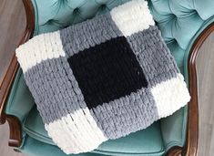 a gray and white blanket sitting on top of a blue chair