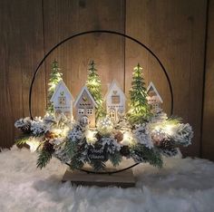 a christmas centerpiece with small houses and evergreens in the center surrounded by lights