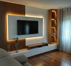 a living room with a large flat screen tv mounted on the wall and wooden flooring