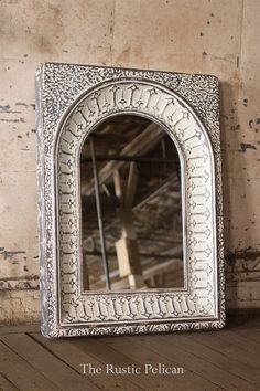 a mirror sitting on top of a wooden floor next to a brick wall with peeling paint