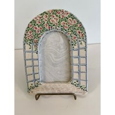 a small white and blue arch with flowers on it's sides is sitting on a table