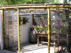 an outdoor area with potted plants and a small table in the center, surrounded by bamboo trelliss