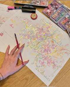 a person is drawing on paper with colored pencils and watercolors next to it