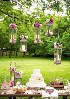 an image of a wedding cake with flowers on it and hanging from the trees in the background