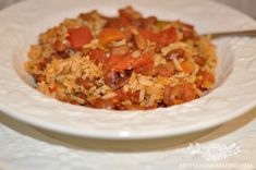 a white bowl filled with rice and vegetables on top of a table next to a fork