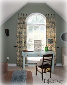 a bedroom with a desk, chair and window covered in curtains on the windowsill