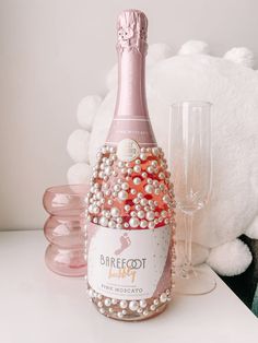 a bottle of champagne with pearls on it next to two glasses and a teddy bear