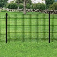 a black wire fence in the middle of a grassy field