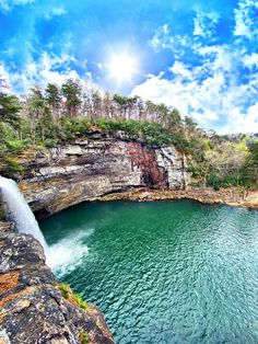 a large body of water with a waterfall in the middle of it and trees on both sides