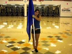 a girl holding a blue flag in the middle of a gym floor with an orange and white checkered floor