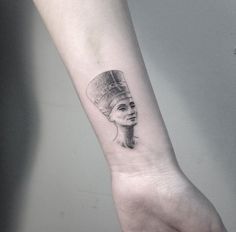 a woman's hand with a small tattoo on the left wrist and an egyptian head