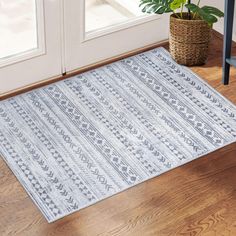 a blue and white rug sitting on top of a wooden floor next to a potted plant