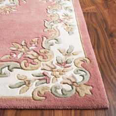 a pink and white rug on the floor with wood floors in the background at home