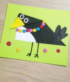 a bird made out of construction paper on top of a green piece of paper with buttons