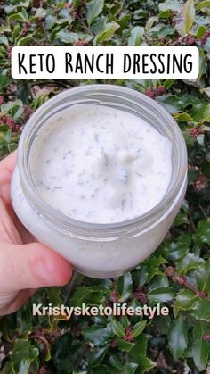 a hand holding a jar of keto ranch dressing in front of some bushes with the words keto ranch dressing above it