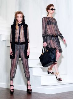 two models are standing on the runway with handbags and purses in their hands