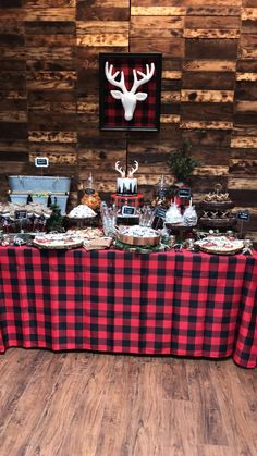 a table covered with food and desserts in front of a deer head mounted on the wall