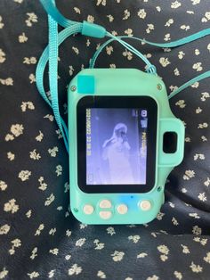 a small child's tablet sitting on top of a floral print bed sheet with a blue strap