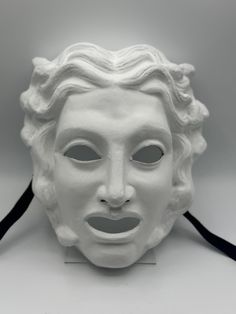 a white mask with black ribbon around it's neck and the face of a woman