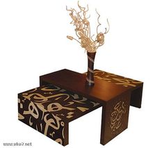 a wooden table with a flower vase on top of it and an ottoman underneath the table