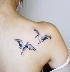 the back of a woman's shoulder with two birds on it