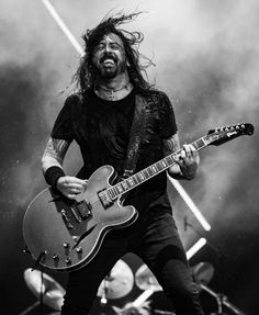 a man with long hair playing an electric guitar