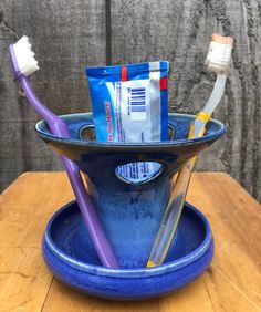 two toothbrushes in a blue bowl on a wooden table