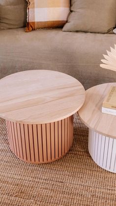 two wooden tables sitting on top of a carpeted floor next to a gray couch