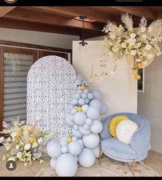 a room decorated with balloons and flowers on the wall, next to a blue chair