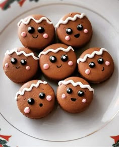 a white plate topped with cookies covered in icing and decorated like faces on top of each other