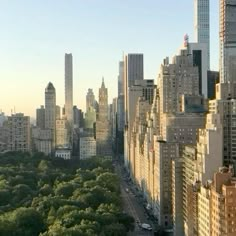 an aerial view of the city skyline with tall buildings and trees in the foreground