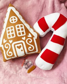 a gingerbread house pillow and candy cane on a pink blanket