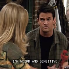 a man talking to a woman in front of a sign that says i'm weird and sensitive