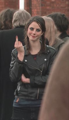 a woman making the vulcan sign while standing in front of a group of other people