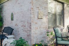 an outdoor patio with chairs and potted plants on the side of the house,