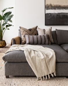 a couch with many pillows on it and a blanket draped over the back of it