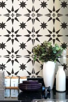 a black and white tiled wall with vases on the counter top next to it