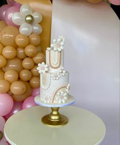 a three tiered cake sitting on top of a table next to balloons and streamers