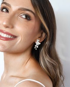 a woman wearing earrings and smiling at the camera