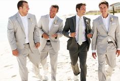 three men in suits are walking on the beach