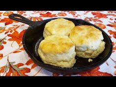 three biscuits in a cast iron skillet on a floral tablecloth with orange flowers