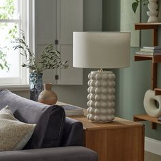 a living room filled with furniture and a lamp on top of a wooden table next to a window