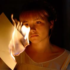 a woman holding a lit candle in front of her face