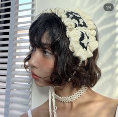 a woman wearing a crochet headband with flowers on it's side