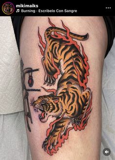 a tiger tattoo on the leg of a person with scissors and an ink pen in it